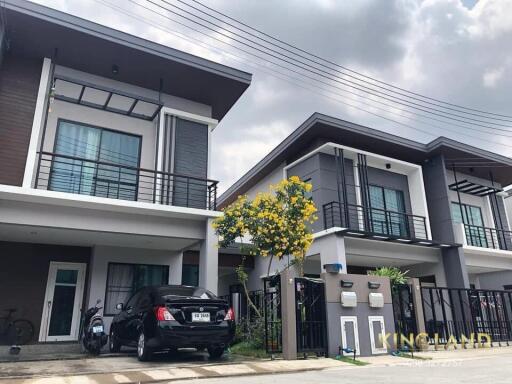 Two modern two-story houses with garages and a tree in between