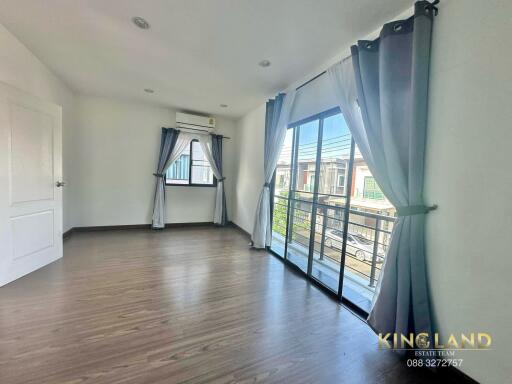 Spacious bedroom with wooden flooring and large windows