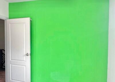 Bedroom with green accent wall and wooden flooring