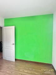 Bedroom with green accent wall and wooden flooring