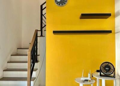 Living area with yellow accent wall and staircase