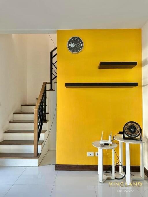 Living area with yellow accent wall and staircase