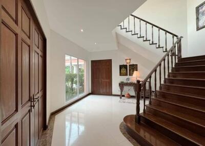 Spacious foyer with wooden stairs and large windows