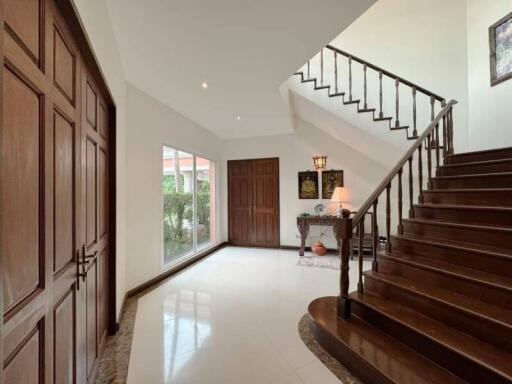 Spacious foyer with wooden stairs and large windows