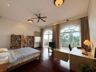 Spacious bedroom with large windows, bookshelves, desk, and bed