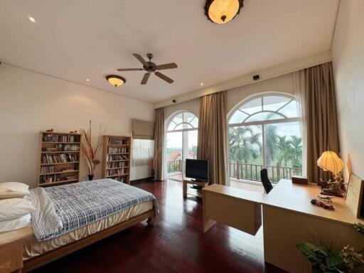 Spacious bedroom with large windows, bookshelves, desk, and bed