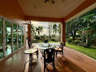 Outdoor patio with glass table and chairs, overlooking garden