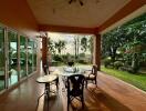 Outdoor patio with glass table and chairs, overlooking garden