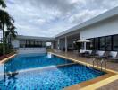 Modern outdoor swimming pool area with lounge chairs and patio umbrella