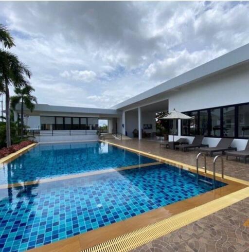 Modern outdoor swimming pool area with lounge chairs and patio umbrella