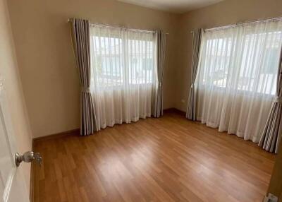 Spacious bedroom with wooden flooring and large windows