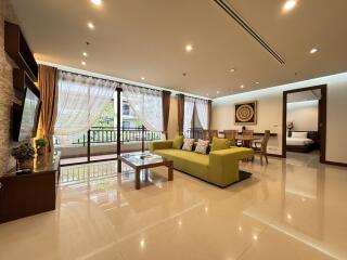 Spacious and well-lit modern living room with green sofa and dining area