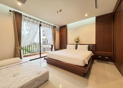 Spacious bedroom with a large window, double bed, and a single bed, featuring wooden furniture and modern decor