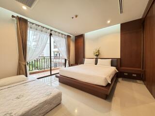 Spacious bedroom with a large window, double bed, and a single bed, featuring wooden furniture and modern decor