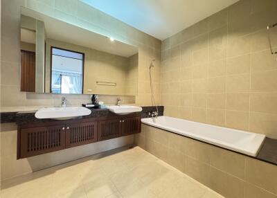 Modern bathroom with large mirror, dual sinks, and bathtub.