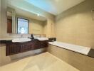 Modern bathroom with large mirror, dual sinks, and bathtub.