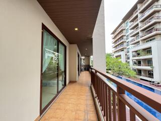 Spacious balcony overlooking a pool with access to neighboring buildings