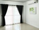 Bright living room with large window, black curtains, and air conditioning unit