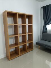 Empty bookshelf and couch in a living room with tiled floor