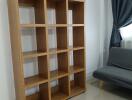 Empty bookshelf and couch in a living room with tiled floor