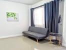 Minimalist living room with gray sofa, side table, and framed artwork