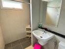 Modern bathroom with stand-alone sink, large mirror, shower area, and window