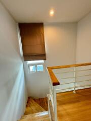 Staircase with wooden steps and handrail, and a window with brown blinds