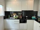 Modern kitchen with white cabinets and black backsplash