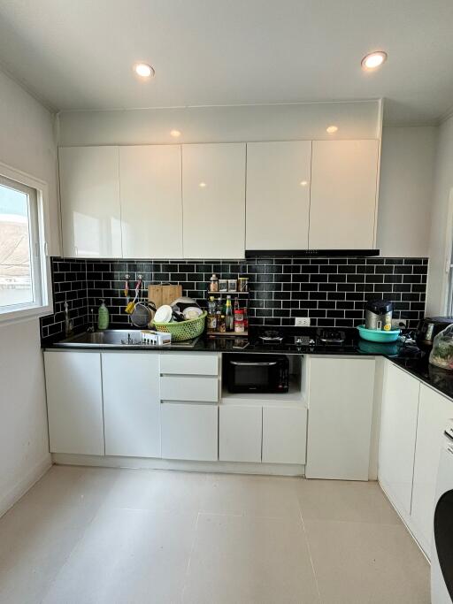 Modern kitchen with white cabinets and black backsplash