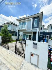 Two-story modern house with a small yard and gated driveway