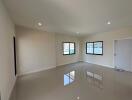 Spacious empty living room with large windows and tiled floor