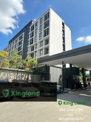 Exterior view of a condominium building on a sunny day with signage 