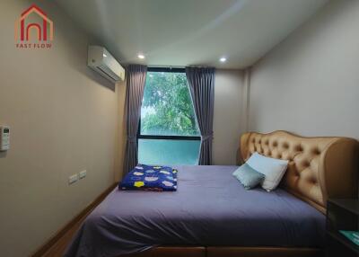 A cozy bedroom with a window, air conditioning, and a tufted headboard bed.