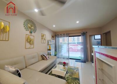 Modern living room with a white sofa, coffee table, decorative wall art, and large windows with curtains