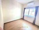 Empty bedroom with wooden floor and window with curtains