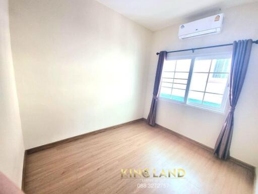 Empty bedroom with wooden floor and window with curtains