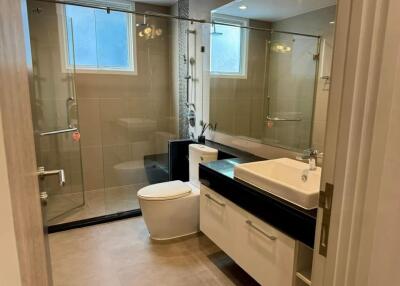 Modern bathroom with glass shower, sink, and toilet