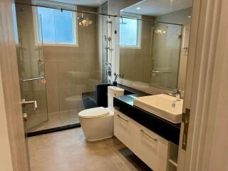 Modern bathroom with glass shower, sink, and toilet