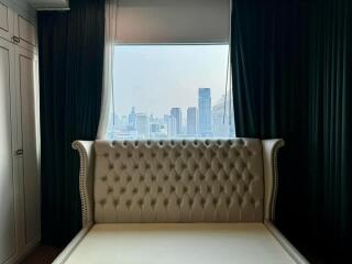 Bedroom with a large tufted headboard and city view