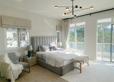 Modern bedroom with large windows, a bed, and sitting area