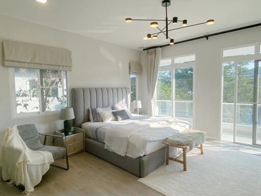 Modern bedroom with large windows, a bed, and sitting area