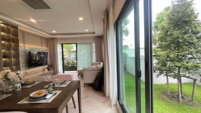 Spacious living room with large windows, dining table, and garden view