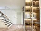 Modern main living area with staircase, glass-fronted cabinet and natural lighting