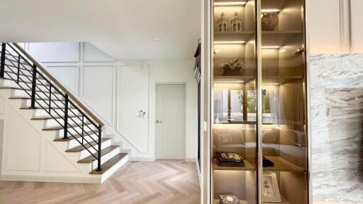 Modern main living area with staircase, glass-fronted cabinet and natural lighting