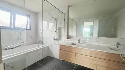 Modern bathroom with bathtub, glass shower partition, dual sinks, and large mirror