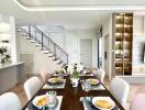 Modern dining area with table setting, adjacent to kitchen and living room