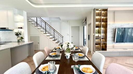 Modern dining area with table setting, adjacent to kitchen and living room