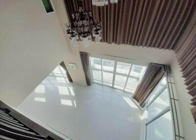 Spacious living room with large windows and chandelier, viewed from above