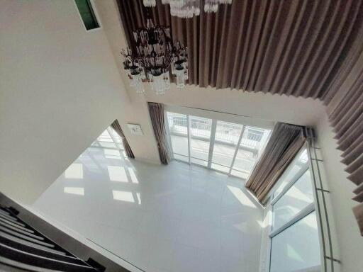 Spacious living room with large windows and chandelier, viewed from above