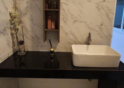 Modern bathroom sink area with marble tiles and shelving